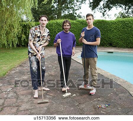Stock Photograph - Portrait of three young men on poolside with brooms. Fotosearch