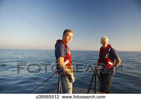 Stock Image - Portrait of two male lifeboat crew at sea. Fotosearch