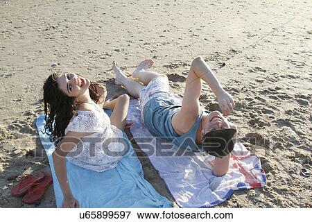 Portrait of young couple on towels on beach, looking up View Large Photo Image Stock Photo - Portrait of young couple on towels on beach, looking up. Fotosearch