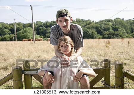 Stock Image - Portrait of young couple with field in background. Fotosearch