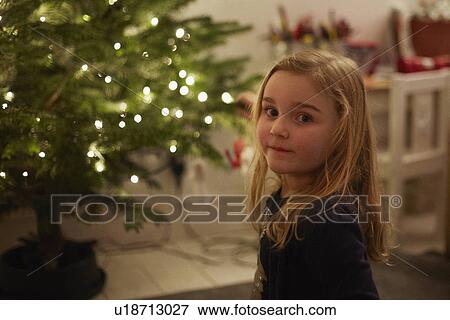 Stock Photo - Portrait of young girl and christmas tree. Fotosearch