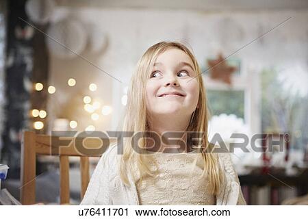 Stock Image - Portrait of young girl in kitchen pulling a face. Fotosearch