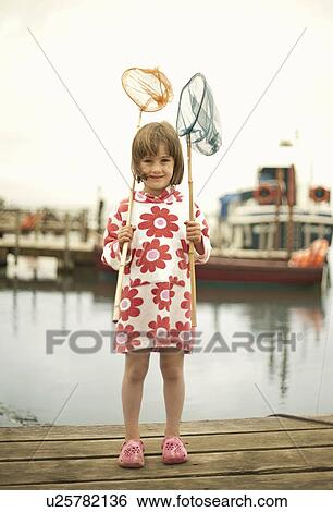 Stock Photograph - Portrait of young girl on pier with fishing nets, Southwold, Suffolk, UK. Fotosearch