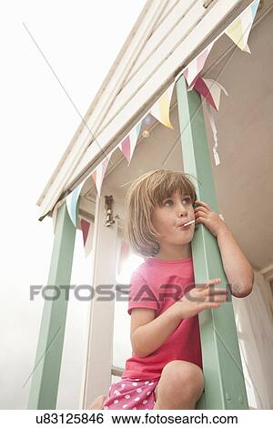 Stock Photograph - Portrait of young girl sucking lollipop, Southwold, Suffolk, UK. Fotosearch