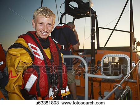 Stock Image - Portrait of young man crewing lifeboat at sea. Fotosearch