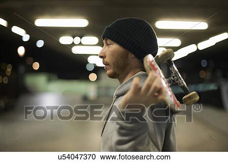 Portrait of young man holding skateboard View Large Photo Image Stock Image - Portrait of young man holding skateboard. Fotosearch