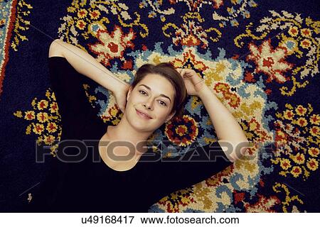 Portrait of young woman lying on patterned rug View Large Photo Image Stock Photo - Portrait of young woman lying on patterned rug. Fotosearch
