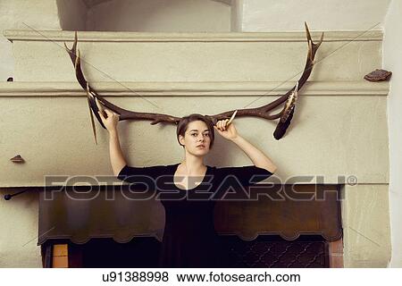 Portrait of young woman standing in front of antlers View Large Photo Image Stock Photo - Portrait of young woman standing in front of antlers. Fotosearch