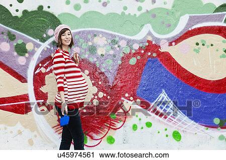 Stock Image - Pregnant woman, graffiti in the background. Fotosearch