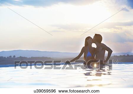 Stock Photograph - Romantic couple kissing in outdoor swimming pool. Fotosearch