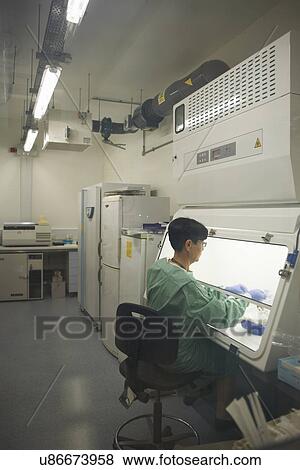Stock Photo - Scientist working behind screen of scientific machine. Fotosearch
