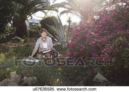 Stock Photography - Senior adult woman drawing in garden. Fotosearch