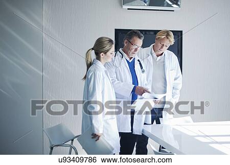Stock Photograph - Senior doctor and trainees looking at medical records. Fotosearch