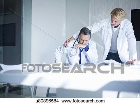 Picture - Senior doctor being comforted by trainee. Fotosearch