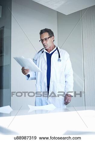 Stock Photo - Senior male doctor reading medical records. Fotosearch