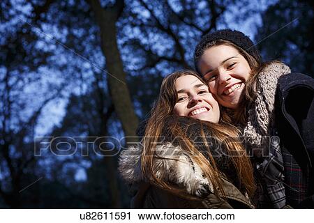 Sisters hugging in forest at dusk View Large Photo Image Stock Image - Sisters hugging in forest at dusk. Fotosearch