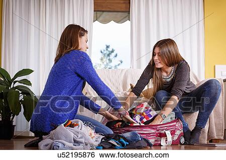 Stock Photograph - Sisters packing luggage in room. Fotosearch