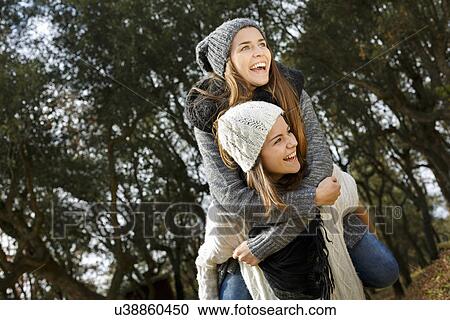 Sisters piggy back riding in forest View Large Photo Image Stock Image - Sisters piggy back riding in forest. Fotosearch