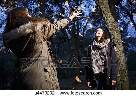 Sisters scattering leaves into air View Large Photo Image Stock Image - Sisters scattering leaves into air. Fotosearch