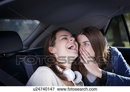 Stock Photo - Sisters whispering in car. Fotosearch