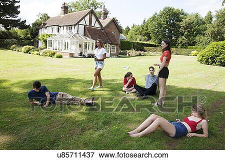 Six young adult friends in garden relaxing View Large Photo Image Stock Photo - Six young adult friends in garden relaxing. Fotosearch