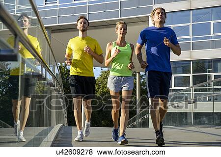 Stock Photo - Small group of adult runners on city footbridge. Fotosearch