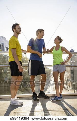 Small group of adult runners taking a break on city footbridge View Large Photo Image Picture - Small group of adult runners taking a break on city footbridge. Fotosearch
