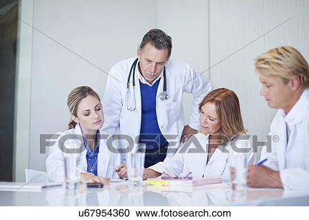 Stock Image - Small group of doctors having a serious meeting. Fotosearch