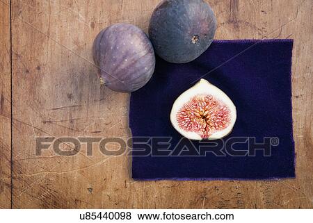 Stock Photo - Still life of three figs, one sliced in half on purple cloth. Fotosearch