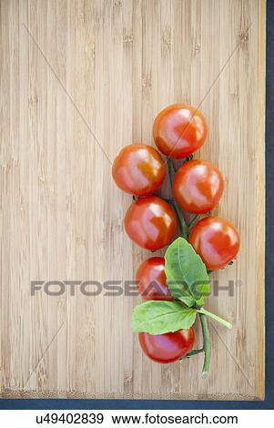 Stock Photo - Still life of vine tomatoes with basil leaf. Fotosearch