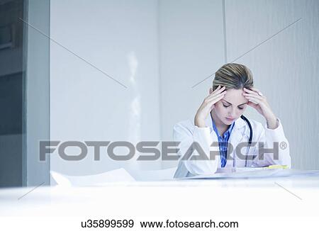 Stressed young female doctor View Large Photo Image Stock Photo - Stressed young female doctor. Fotosearch