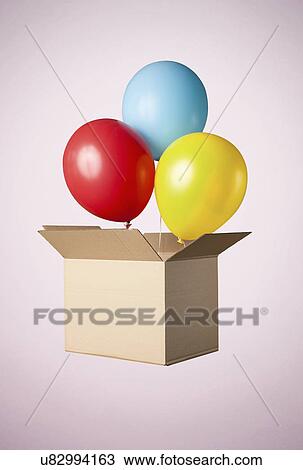 Stock Image - Studio shot of cardboard box with balloons coming out. Fotosearch