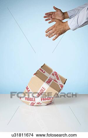 Studio shot of hands dropping cardboard box marked fragile View Large Photo Image Picture - Studio shot of hands dropping cardboard box marked fragile. Fotosearch