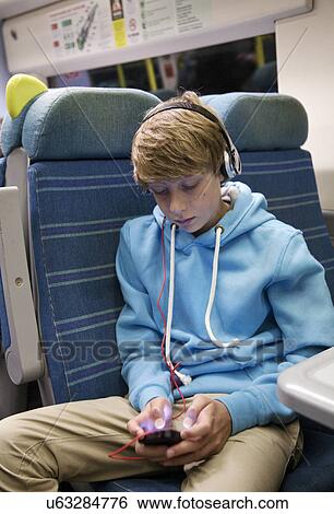 Teenage boy with headphones and smartphone on train View Large Photo Image Stock Photograph - Teenage boy with headphones and smartphone on train. Fotosearch