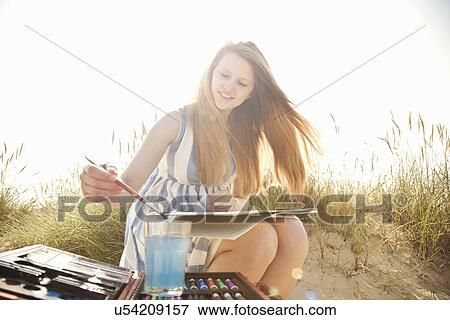 Stock Photo - Teenage girl drawing on the beach. Fotosearch