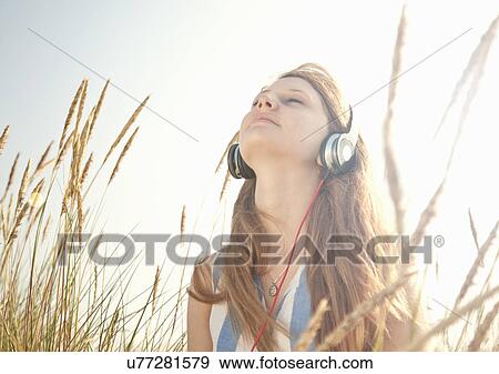 Stock Photo - Teenage girl listening to music outdoors. Fotosearch