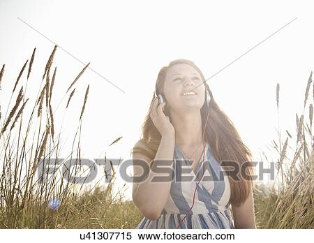 Stock Photography - Teenage girl listening to music outdoors. Fotosearch