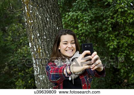 Stock Photo - Teenage girl self-photographing in forest. Fotosearch