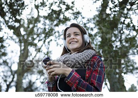 Stock Photo - Teenage girl using mp3 in forest. Fotosearch