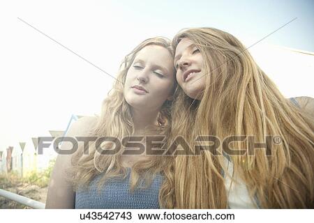 Stock Image - Teenage girls, beach huts in background, Southwold, Suffolk, UK. Fotosearch