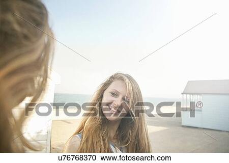 Stock Image - Teenage girls, beach huts in background, Southwold, Suffolk, UK. Fotosearch