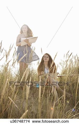Picture - Teenage girls drawing on the beach. Fotosearch