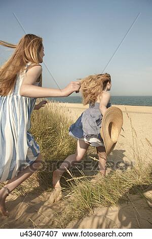 Stock Photo - Teenage girls running to the beach, Southwold, Suffolk, UK. Fotosearch