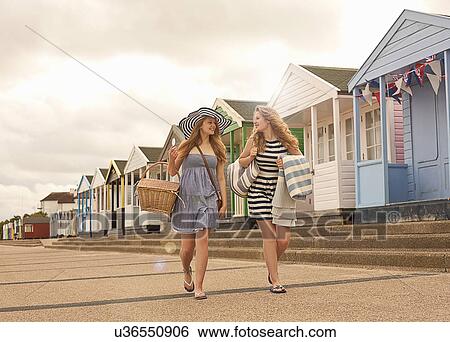Teenage girls walking in front of beach huts with picnic basket View Large Photo Image Stock Photograph - Teenage girls walking in front of beach huts with picnic basket. Fotosearch