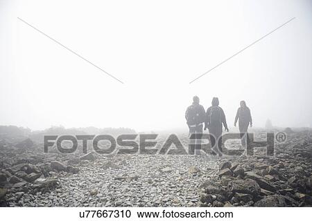 Stock Image - Three people walking through fog, Ben Nevis, Scotland. Fotosearch