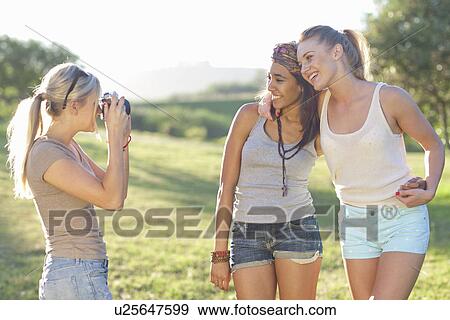 Stock Photo - Three young female friends posing for photographs. Fotosearch