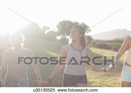 Three young females friends holding hands in sunlight View Large Photo Image Stock Photography - Three young females friends holding hands in sunlight. Fotosearch