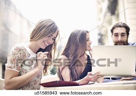 Stock Image - Tourist friends enjoying a break at sidewalk cafe, Valencia, Spain. Fotosearch