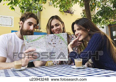 Stock Photo - Tourist friends looking at map at sidewalk cafe, Valencia, Spain. Fotosearch