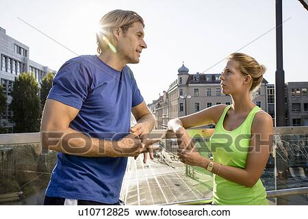 Stock Photography - Two adult runners taking a break on city footbridge. Fotosearch